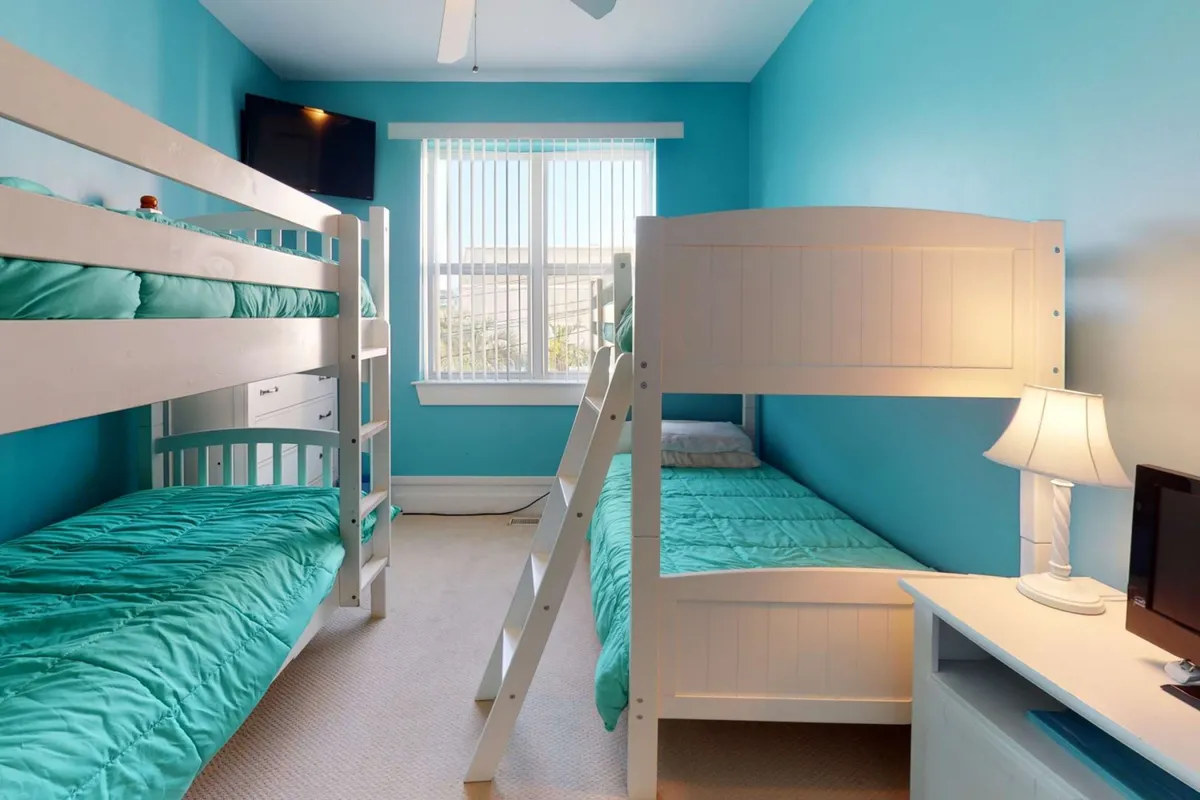 A playful bunk room designed for children, complete with cozy bunk beds, a bedside lamp for reading, and a wall-mounted TV. The cheerful décor makes this an inviting space for kids to unwind and bond.