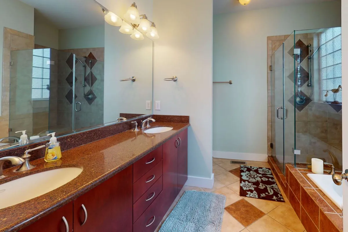 A modern, serene bathroom with a double vanity, spacious glass-enclosed shower, and an inviting bathtub. The clean lines and soothing tones evoke a spa-like experience.